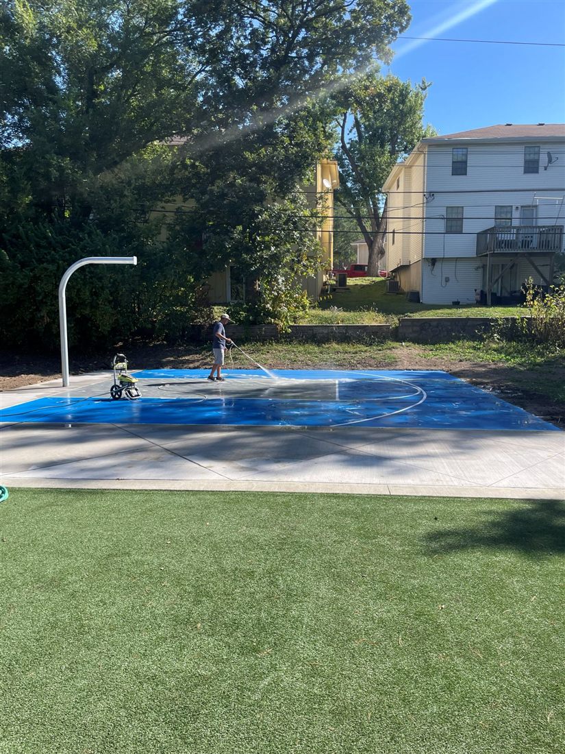 Finished blue sport court with basketball hoop and artificial turf border at Kessler Park, built by Kansas Construction Services